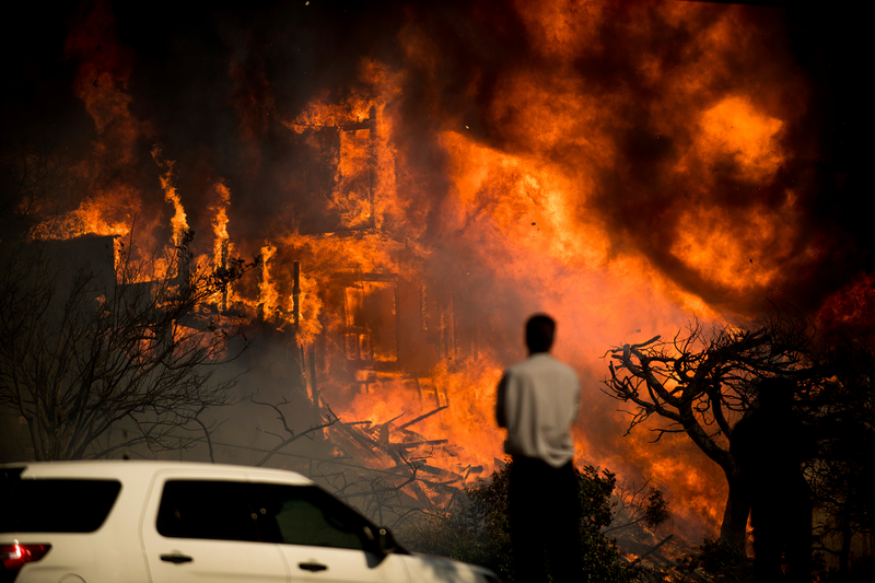 A man watches flames consume a home in Ventura. (Image: AP)